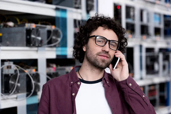 Ingeniero informático guapo hablando por teléfono en la granja minera Etereum - foto de stock