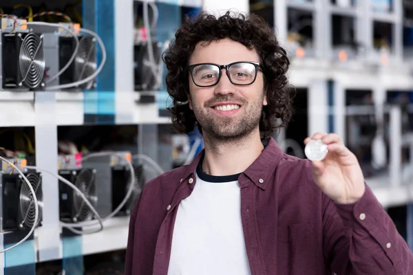 Joven ingeniero informático que sostiene bitcoin en la granja minera criptomoneda - foto de stock