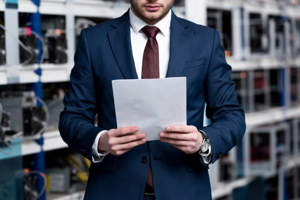 Tiro cortado de jovem empresário com papelada na fazenda de mineração criptomoeda — Fotografia de Stock