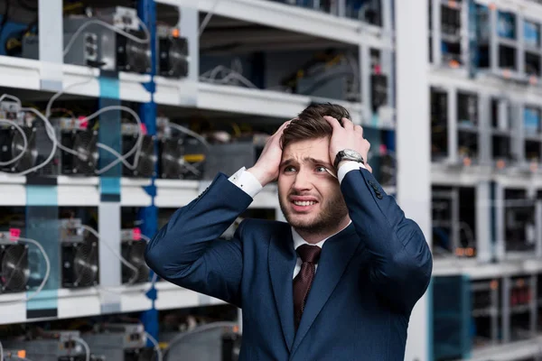 Failed young businessman holding head at cryptocurrency mining farm — Stock Photo