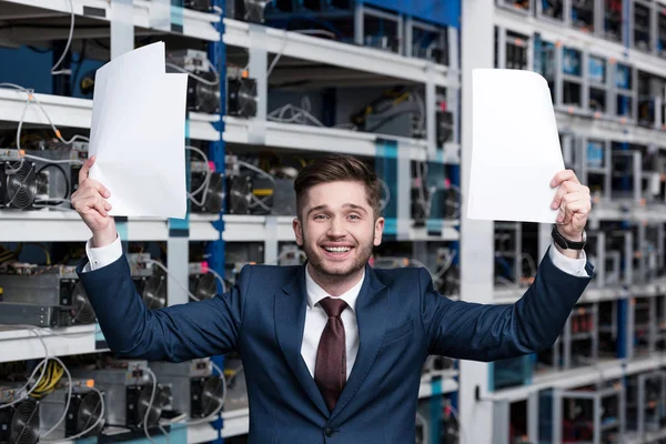 Succès jeune homme d'affaires avec des papiers célébrant la victoire à la ferme minière crypto-monnaie — Stock Photo