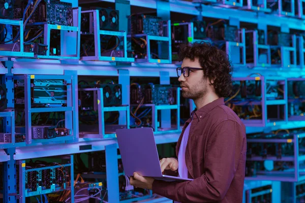 Jeune ingénieur en informatique travaillant avec un ordinateur portable à la ferme minière éthérique — Photo de stock