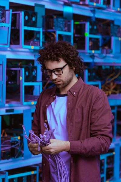 Bel ingénieur en informatique avec fils Ethernet à la ferme minière d'Ethereum — Photo de stock