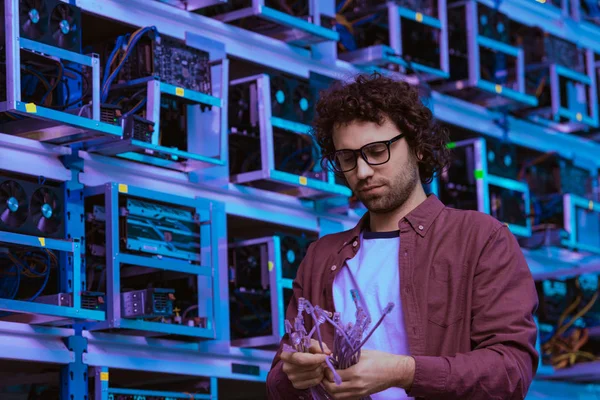 Joven ingeniero informático con cables de Ethernet en la granja minera Etereum — Stock Photo