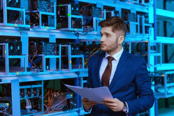 Successful young businessman reading documents at ethereum mining farm — Stock Photo