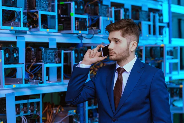 Успішний молодий бізнесмен розмовляє по телефону на гірничодобувній фермі Ethereum — стокове фото
