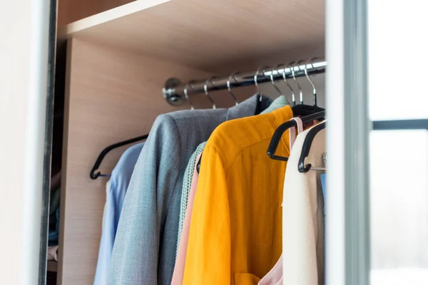 Roupas femininas coloridas penduradas no rack no armário — Fotografia de Stock