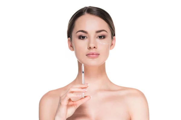 Attraktive junge Frau mit gestrichelten Linien im Gesicht für plastische Chirurgie hält Spritze isoliert auf weiß — Stockfoto