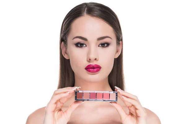 Beautiful young woman holding palette of makeup shadows isolated on white — Stock Photo