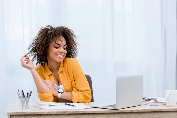 Jeune femme métisse regardant ordinateur portable sur le lieu de travail — Photo de stock