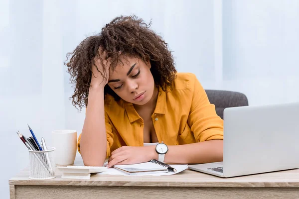 Mujer joven sobrecargada de trabajo sentada en el lugar de trabajo - foto de stock