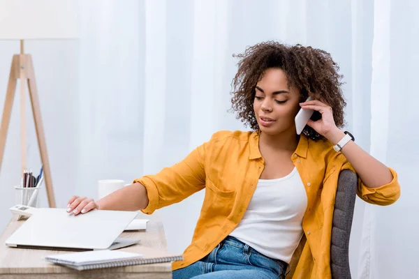 Mujer joven afroamericana hablando por teléfono en el lugar de trabajo - foto de stock