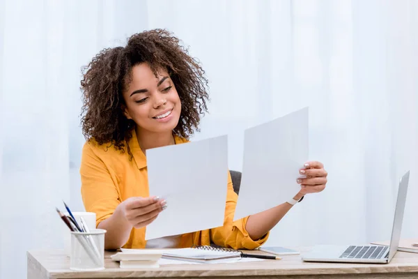 Улыбающаяся молодая женщина делает бумажную работу в офисе — стоковое фото