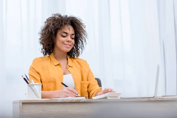 Bella giovane donna che lavora con calcolatrice e laptop e prendere appunti — Foto stock