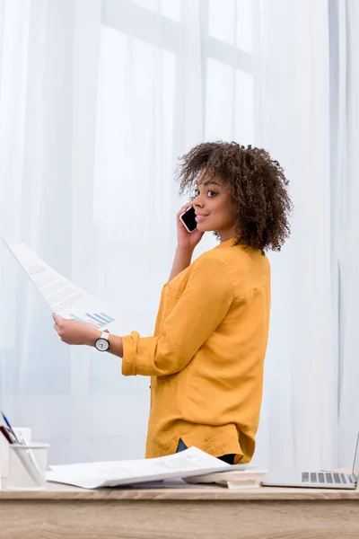 Mulher feliz com papéis de negócios falando por telefone — Fotografia de Stock