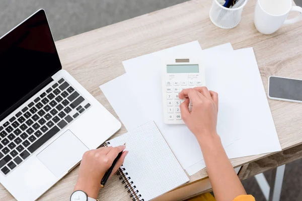 Tiro recortado de mulher que trabalha com calculadora no local de trabalho — Fotografia de Stock