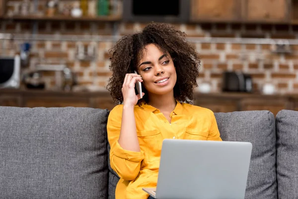 Jeune femme travaillant et parlant par téléphone à la maison sur le canapé — Photo de stock