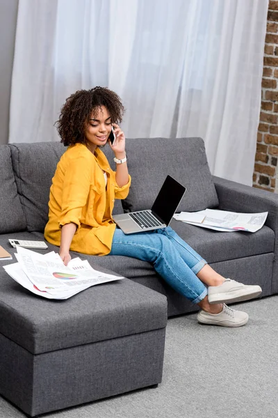 Beautiful young woman working and talking by phone at home on couch — Stock Photo