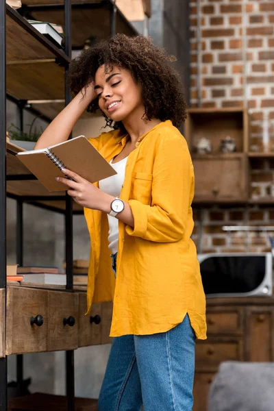 Happy young woman reading book at home — Stock Photo
