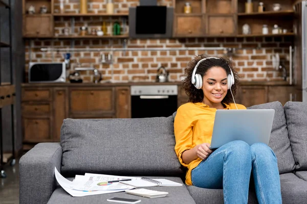 Atractiva joven mujer que trabaja con el ordenador portátil y escuchar música en casa - foto de stock