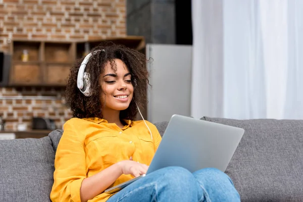 Feliz joven mujer que trabaja con el ordenador portátil y escuchar música en casa - foto de stock