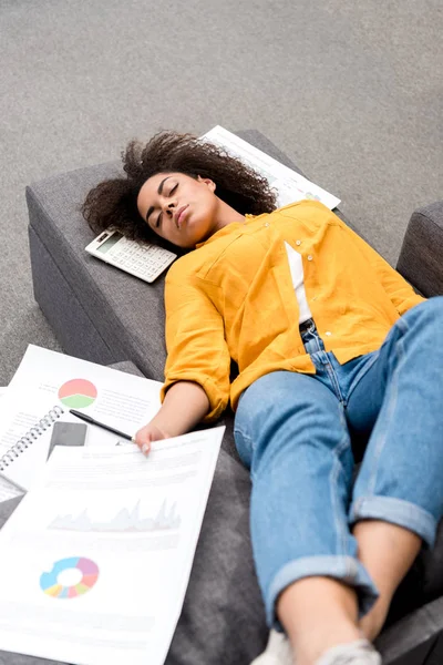 Jeune femme surmenée dormant sur le canapé après le travail à la maison — Photo de stock