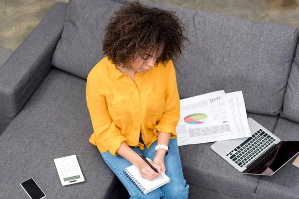 High angle view of young woman working at home on couch — Stock Photo