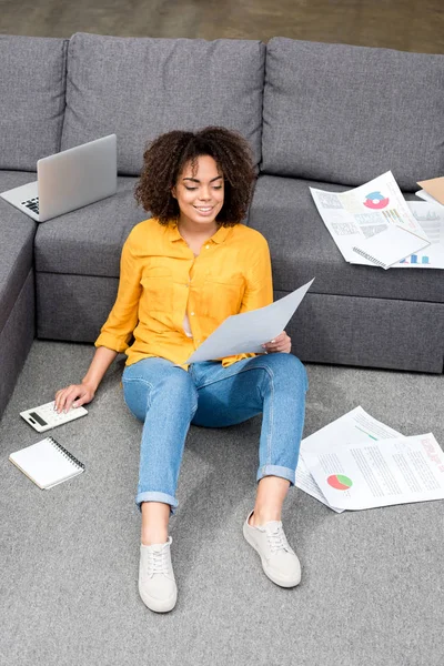 Schöne junge Frau sitzt zu Hause auf dem Boden und arbeitet — Stockfoto