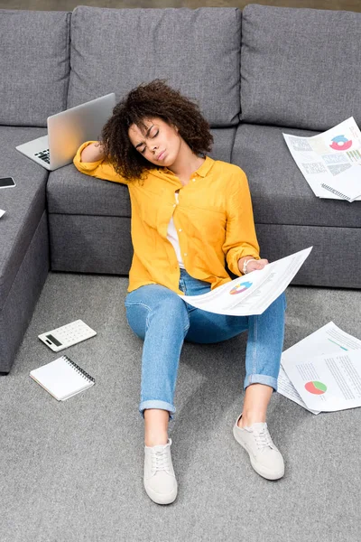 Schöne junge Frau sitzt zu Hause auf dem Boden und erledigt Papierkram — Stockfoto