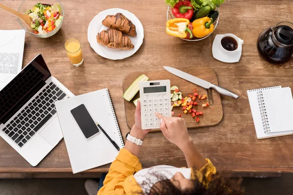 Top view of young woman working with digital devices at kitchen during breakfast — Stock Photo