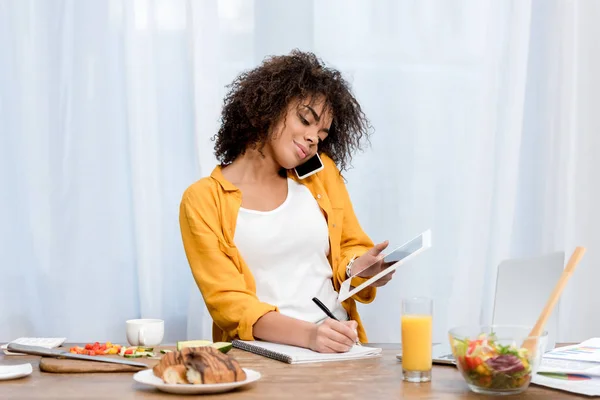 Jeune femme afro-américaine travaillant à la maison pendant le petit déjeuner — Photo de stock