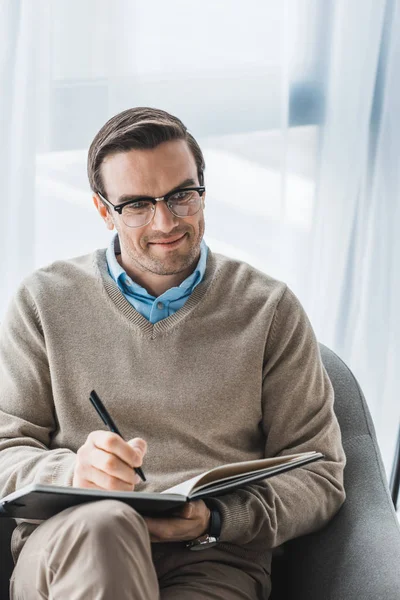 Male psychologist in glasses writing down patient complaints — Stock Photo