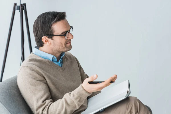 Мужской терапевт в очках слушает пациента в офисе — стоковое фото
