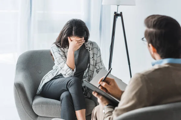 Stressed woman sitting in chair at male doctor office — Stock Photo