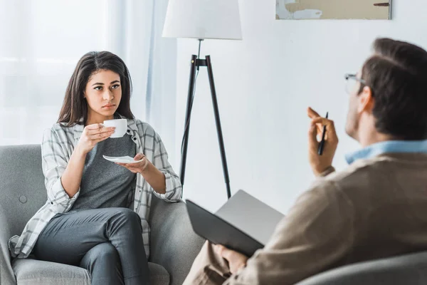 Woman drinking coffee and listening to male doctor recommendations — Stock Photo