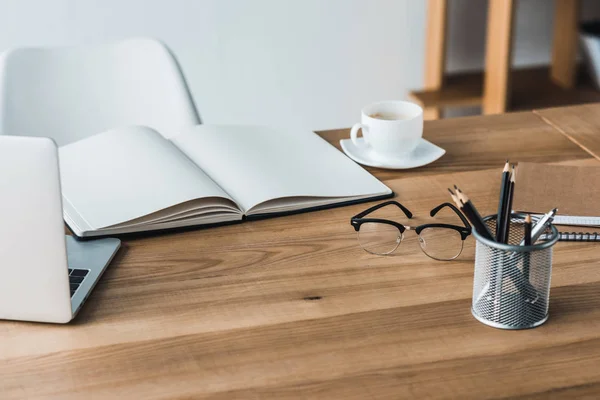 Table de travail avec ordinateur portable et papeterie dans le bureau — Photo de stock