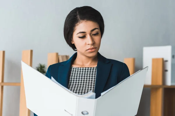 Confident businesswoman looking at folder in modern office — Stock Photo