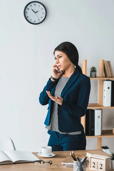 Junge Geschäftsfrau telefoniert mit Tisch im hellen Büro — Stockfoto