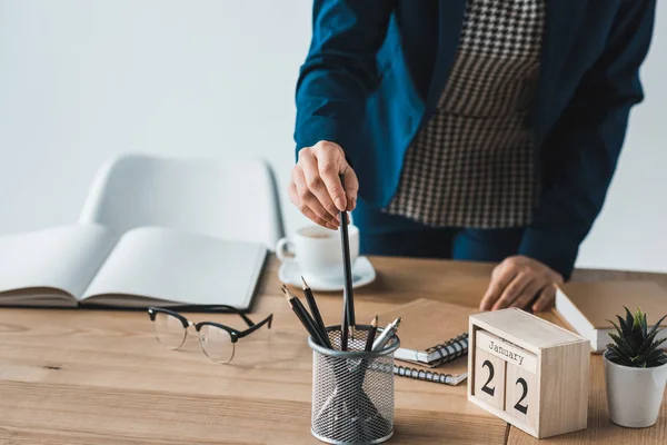 Vista recortada de la mujer que elige el lápiz en la mesa de la oficina — Stock Photo