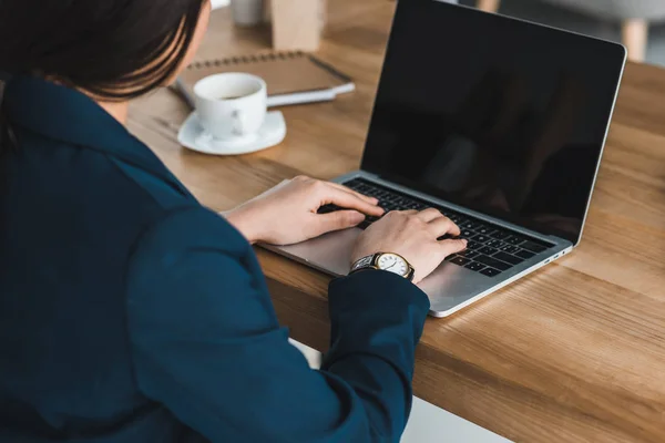 Rear view of businesswoman typing on laptop by table in office — Stock Photo