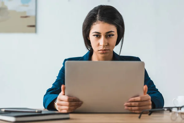 Empresária séria trabalhando por laptop no escritório — Fotografia de Stock