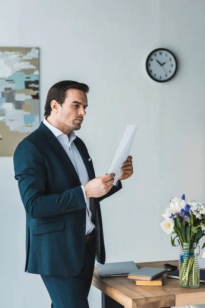 Pensativo hombre de negocios mirando los papeles del contrato en la oficina - foto de stock