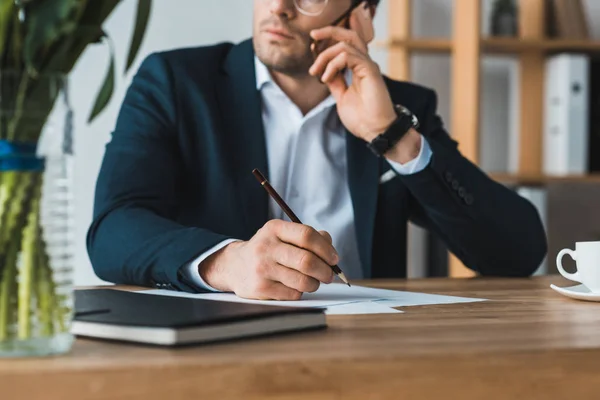 Adult male manager  working by table and talking on the phone in office — Stock Photo