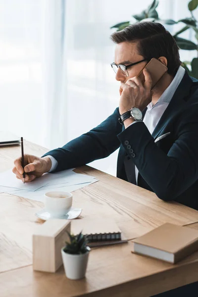 Businessman working by table and talking on the phone — Stock Photo