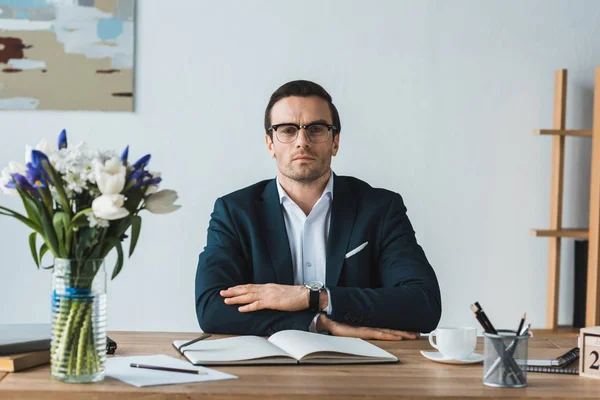 Serious businessman sitting straight by working table — Stock Photo