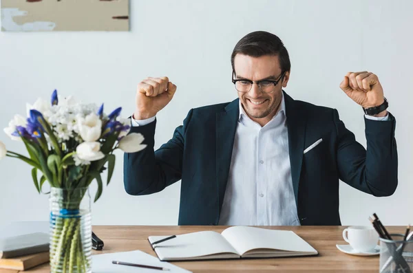 Щасливий бізнесмен дивиться на блокнот на офісному столі — стокове фото