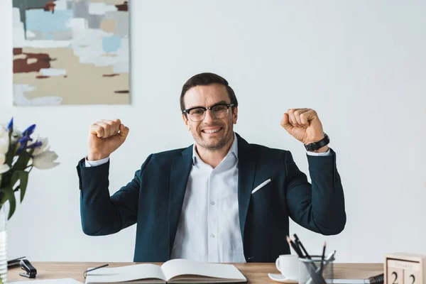 Homme d'affaires excité dans des lunettes par table de travail — Photo de stock