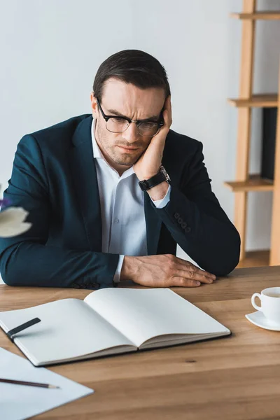 Empresário perturbado apoiado na mesa de trabalho — Fotografia de Stock