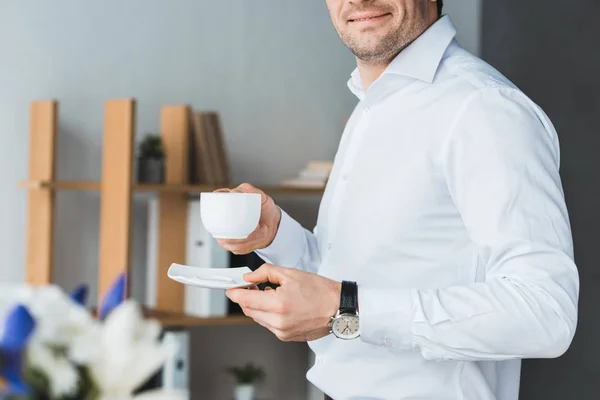 Vista de cerca del hombre de negocios sosteniendo la taza con café en la oficina - foto de stock