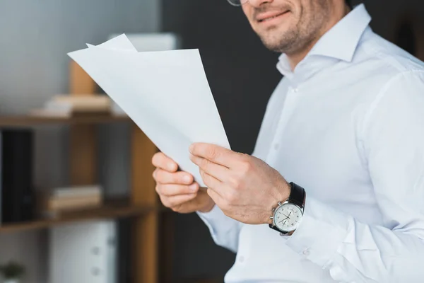 Empresário sorridente estudando papéis no escritório — Fotografia de Stock